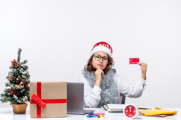 Free photo front view female worker sitting before her working place holding bank card job business work christmas office holiday