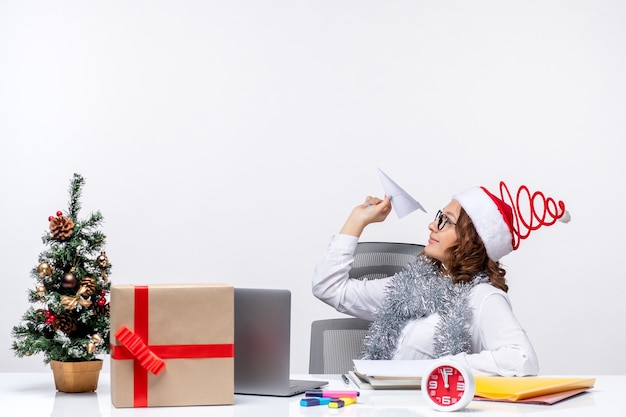 Free photo front view female worker sitting before her working place playing with paper planes work job emotions business office xmas