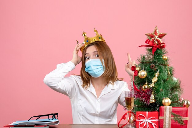 Front view of female worker in sterile mask with crown on pink