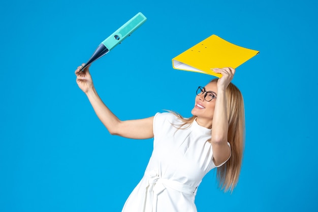 Free photo front view of female worker in white dress holding different folder on blue wall