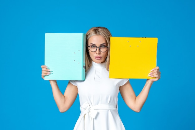 Free photo front view of female worker in white dress holding different folder on blue wall