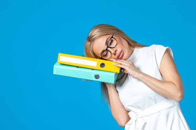 Free Photo front view of female worker in white dress holding different folder on blue wall