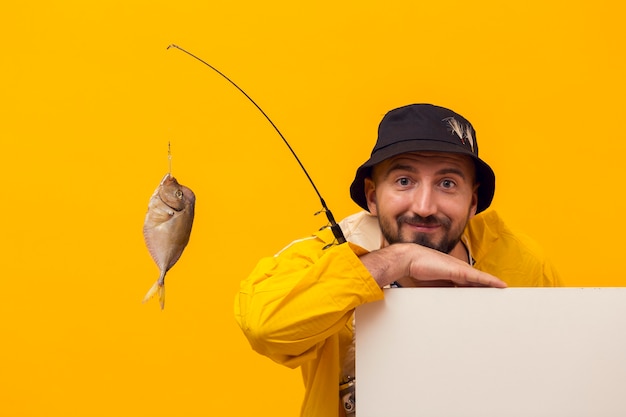 Free Photo front view of fisherman posing while holding fishing rod with catch