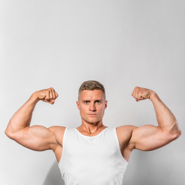 Free photo front view of fit man showing biceps with copy space