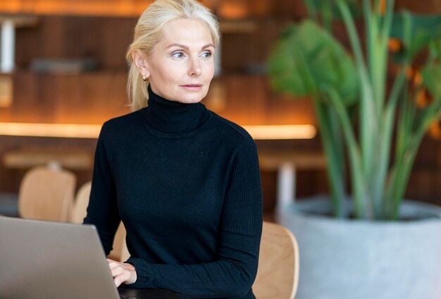 Front view of focused older woman working on laptop