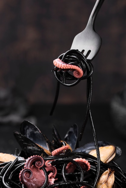 Free photo front view of fork with black pasta and squid