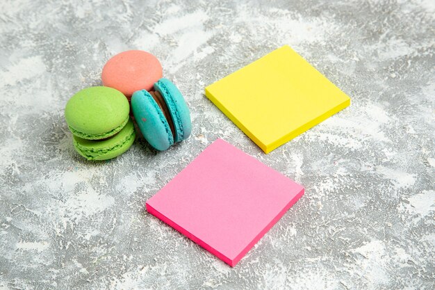 Front view french macarons colorful cakes with stickers on white surface cake pie sugar bake biscuit sweet cookies