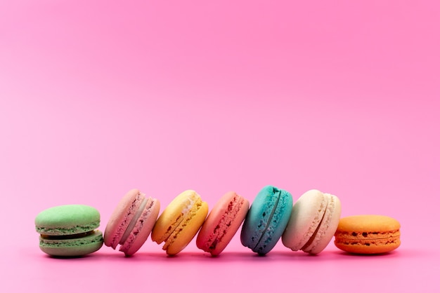 A front view french macarons round delicious colorful isolated on pink, cake biscuit confectionery