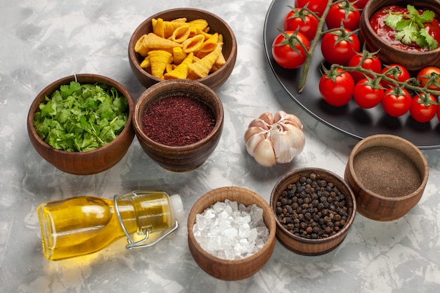 Free photo front view fresh cherry tomatoes inside plate with different seasonings on white surface vegetable meal food salad