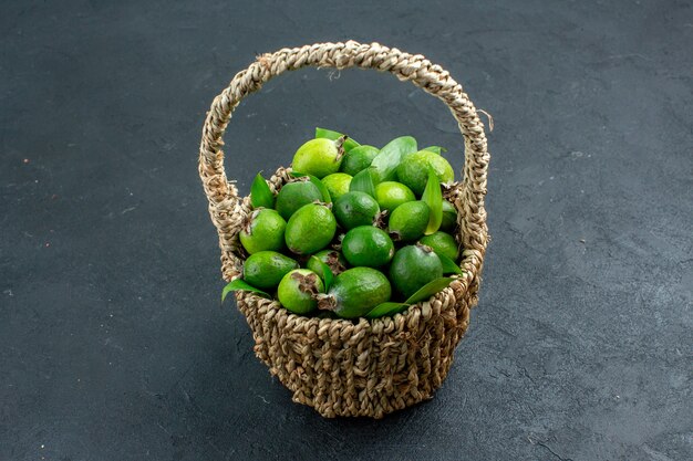 Front view fresh feijoas in basket on dark surface free space