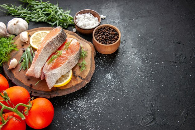 Front view fresh fish slices with tomatoes and lemon slices on dark meat color seafood dish photo food raw