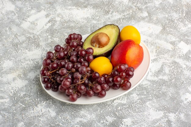 Front view fresh fruits grapes peach and avocado inside plate on white surface