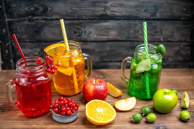 Free photo front view fresh fruity juice orange feijoa and cranberry drinks inside cans on brown desk drink photo cocktail color fruits