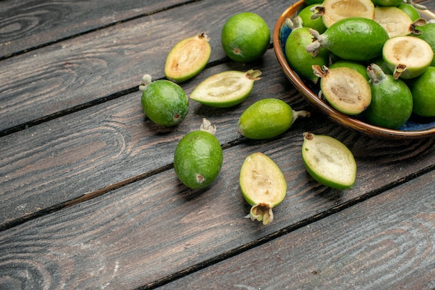 Front view fresh green feijoas inside plate on a wooden rustic desk fruit color photo juice ripe sour