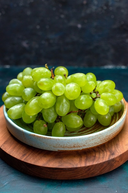 Front view fresh green grapes mellow and juicy fruits inside plate on dark-blue desk.