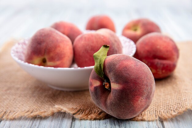 Front view of fresh juicy and delicious peaches on a white bowl with peaches isolated on white surface