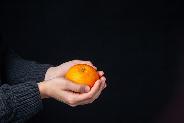 Front view fresh orange in male hands on dark