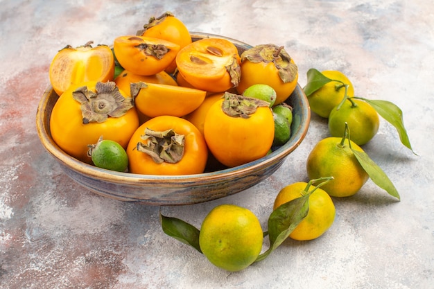 Front view fresh persimmons feykhoas in a bowl and mandarines on nude