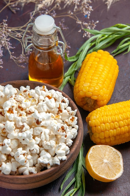 Free photo front view fresh popcorn with raw yellow corns on dark surface snack popcorn corn movie plant