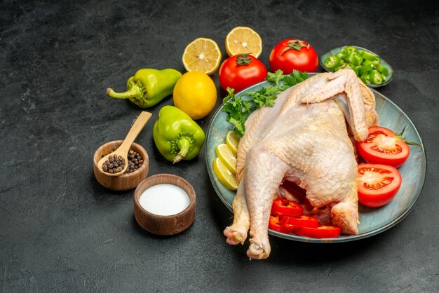 Front view fresh raw chicken inside plate with greens lemon and vegetables on dark background food color meat photo bird animal