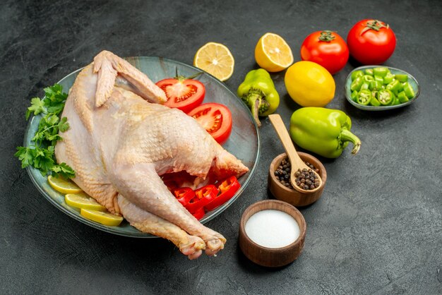 Front view fresh raw chicken with greens lemon and vegetables on dark background bird food color meat photo animal