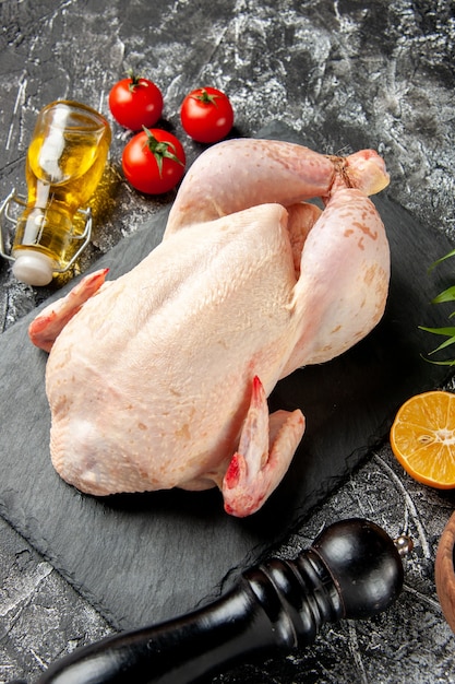 Front view fresh raw chicken with tomatoes on the light-dark kitchen meal animal photo chicken meat color farm food