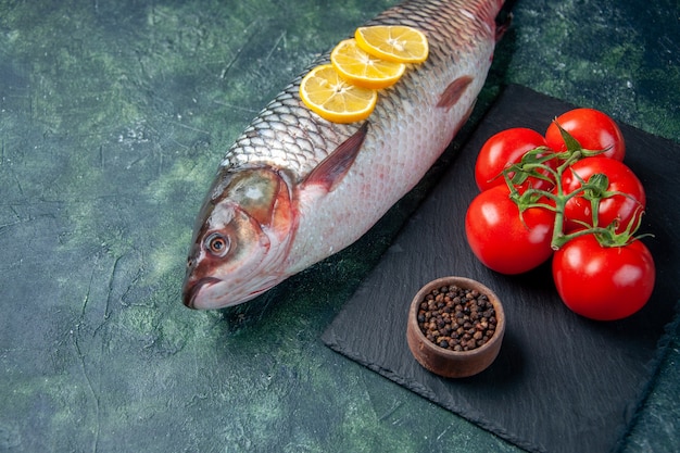 Free photo front view fresh raw fish with lemon slices and tomatoes on dark blue surface shark seafood meal ocean horizontal water meat dinner food