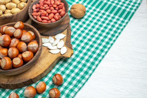 Front view fresh raw hazelnuts with peanuts on white surface