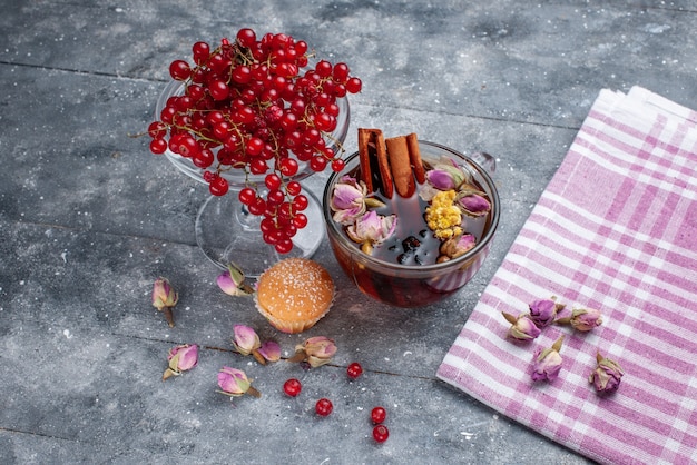 Front view fresh red cranberries with cup of tea and cinnamon on the light desk fruit berry fresh tea