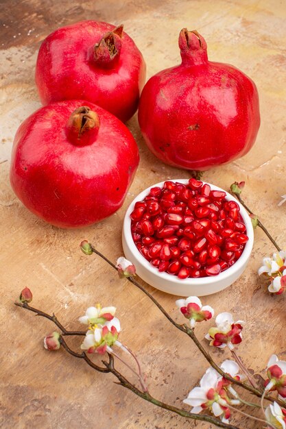 Front view fresh red pomegranates peeled and with whole fruits on brown background color fruit photo mellow juice