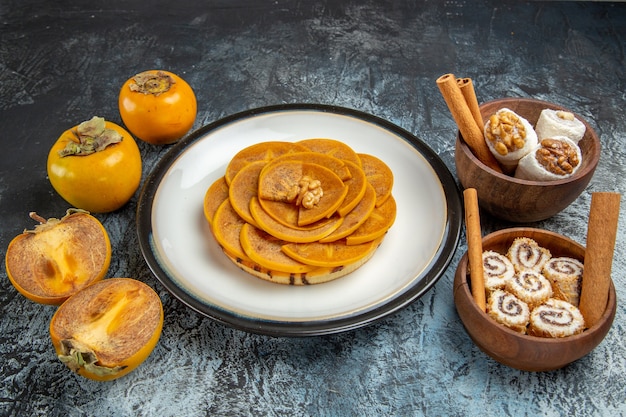 Front view of fresh sliced persimmons with confitures on dark surface