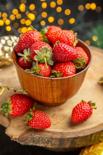 Front view fresh strawberries around christmas toys on a dark background fruit taste xmas photo dark