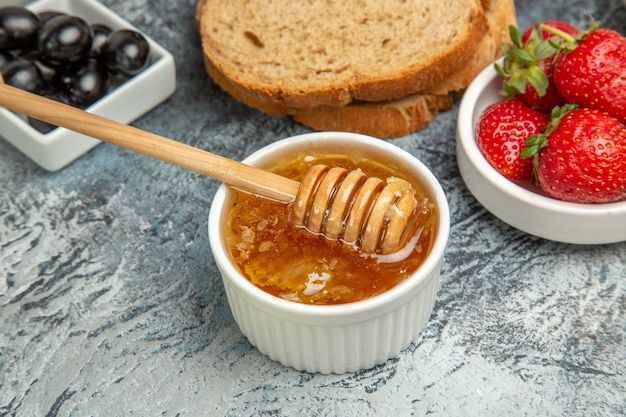 Front view fresh strawberries with tea bread and honey on dark floor fruit sweet food