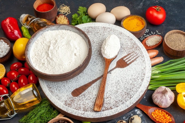 Front view of fresh vegetables fallen oil bottle salt pepper green bundle around cutting board with flour in a brown pot