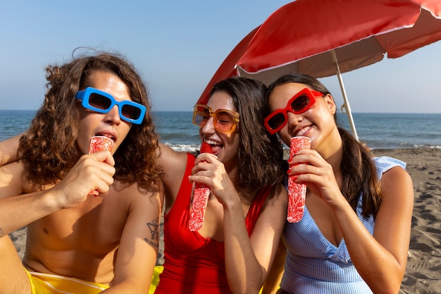 Free photo front view friends eating ice cream on beach