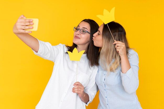 Front view of friends taking selfies with crown