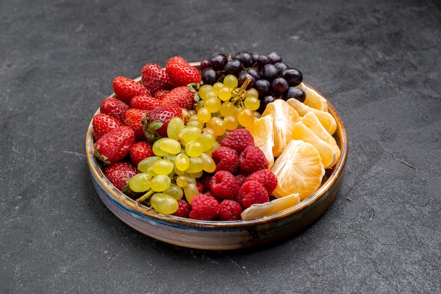 Front view fruit composition strawberries grapes raspberries and tangerines inside tray on dark space