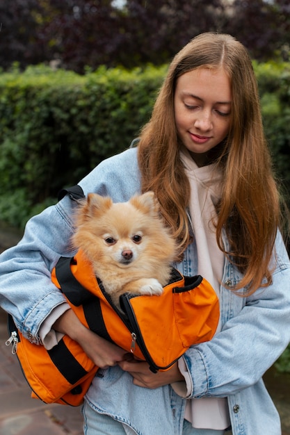 Front view girl carrying puppy in bag