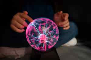 Free photo front view girl interacting with a plasma ball