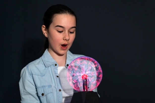 Front view girl interacting with a plasma ball