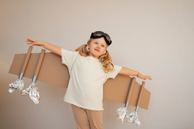 Front view girl playing with cardboard wings