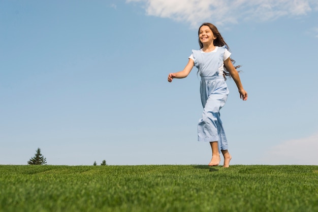 Front view girl running barefoot on grass