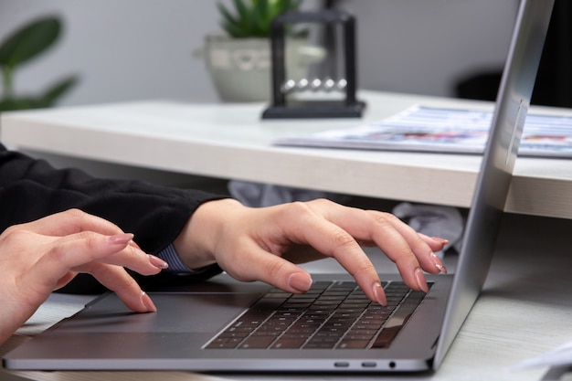 A front view girl using laptop in front of table with schedules and graphics and using laptop job business activity