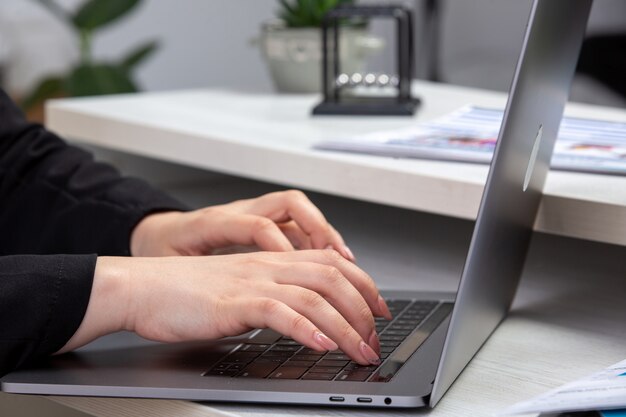 A front view girl using laptop in front of table with schedules and graphics and using laptop job business activity