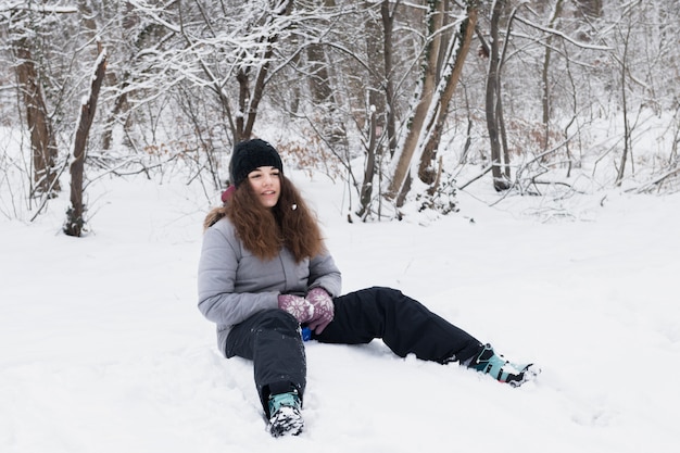 Free Photo front view of girl wearing warm clothes sitting on snow