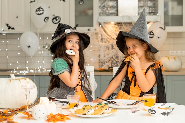 Front view of girls eating halloween cookies