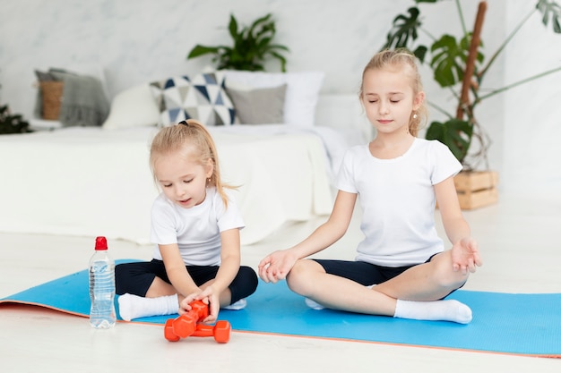 Front view of girls exercising at home on yoga mat