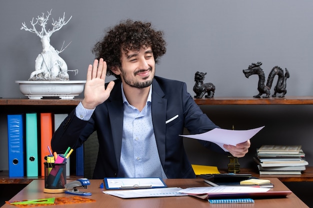 Front view glad businessman hailing someone in his office