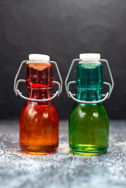 Free photo front view glass cans with liquid inside on a grey table