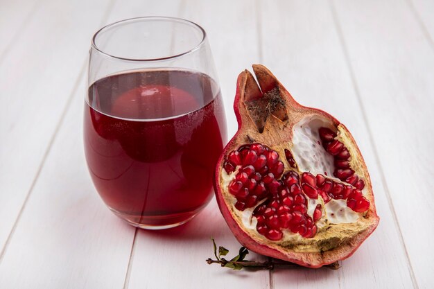 Front view glass of pomegranate juice with pomegranate slice on white wall